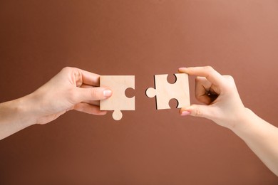 Photo of Business strategy and teamwork concept. Partners putting puzzle pieces together on brown background, closeup