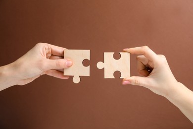 Photo of Business strategy and teamwork concept. Partners putting puzzle pieces together on brown background, closeup