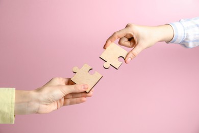 Photo of Business strategy and teamwork concept. Partners putting puzzle pieces together on pink background, closeup