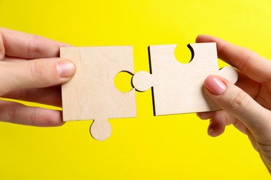 Photo of Business strategy and teamwork concept. Partners putting puzzle pieces together on yellow background, closeup