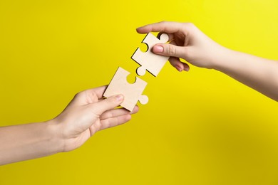 Photo of Business strategy and teamwork concept. Partners putting puzzle pieces together on yellow background, closeup