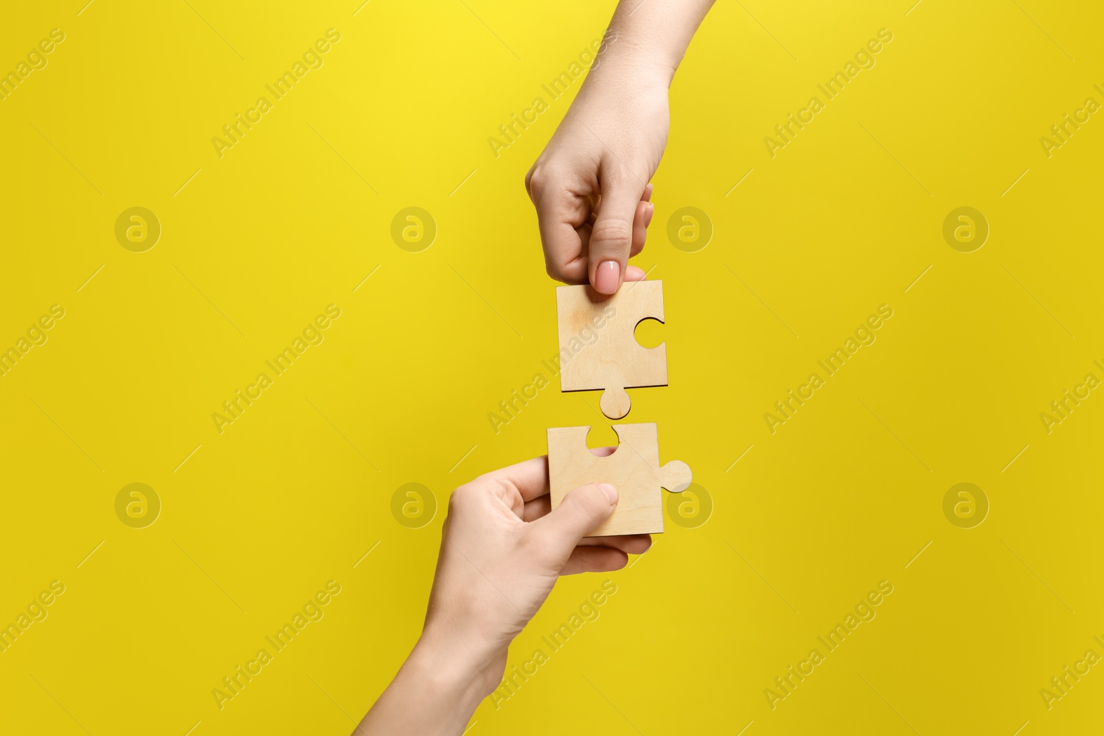 Photo of Business strategy and teamwork concept. Partners putting puzzle pieces together on yellow background, closeup