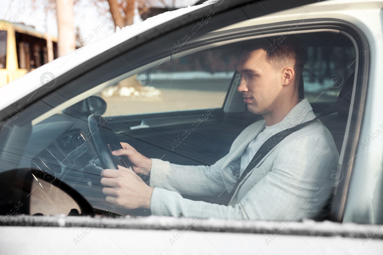 Photo of Driver behind steering wheel of modern car, view from outside