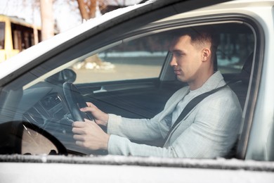 Photo of Driver behind steering wheel of modern car, view from outside