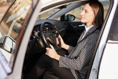 Photo of Driver behind steering wheel of modern car, view from outside