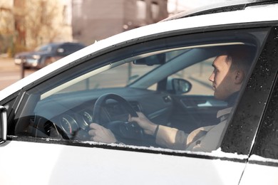 Photo of Driver behind steering wheel of modern car, view from outside