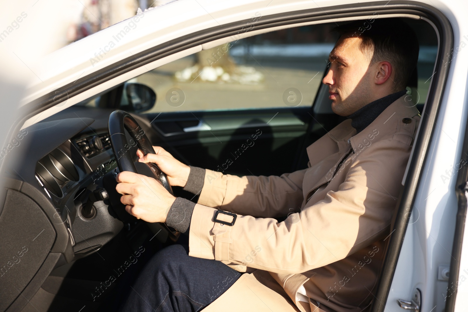 Photo of Driver behind steering wheel of modern car, view from outside