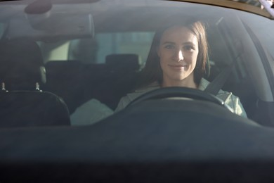 Photo of Driver behind steering wheel of modern car, view from windshield