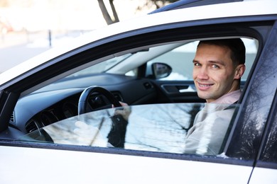 Photo of Driver behind steering wheel of modern car, view from outside