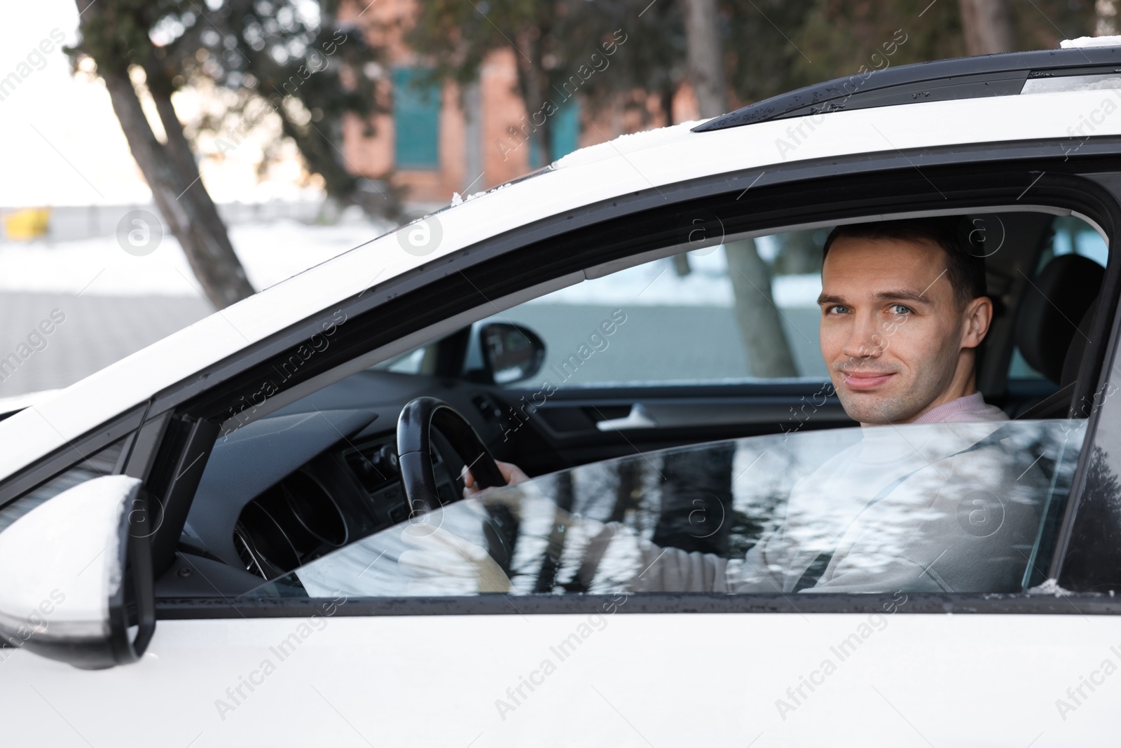 Photo of Driver behind steering wheel of modern car, view from outside