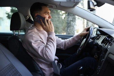 Photo of Driver talking on smartphone while driving modern car