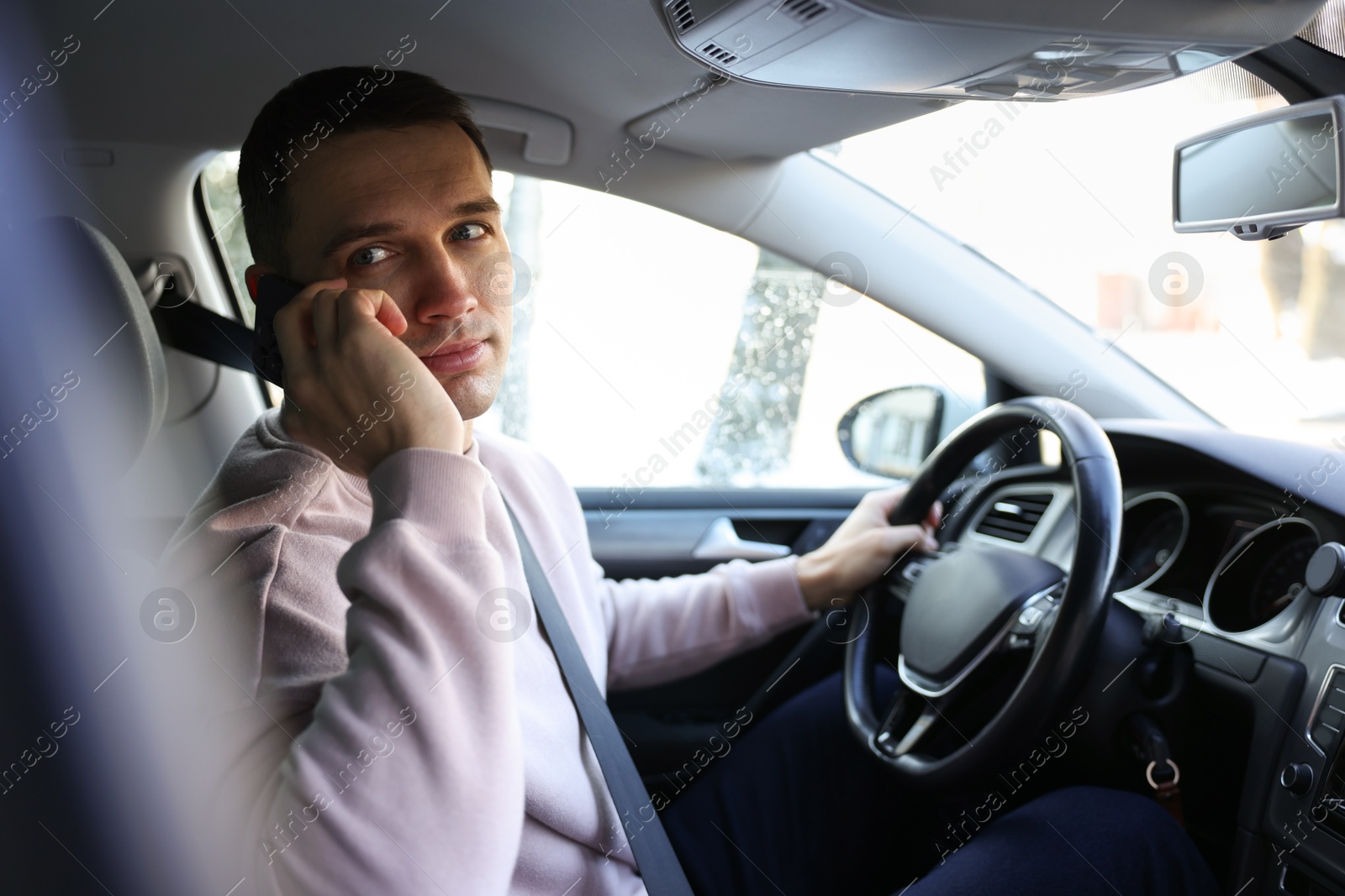 Photo of Driver talking on smartphone while driving modern car, view from window