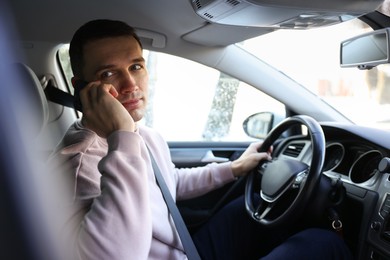 Photo of Driver talking on smartphone while driving modern car, view from window