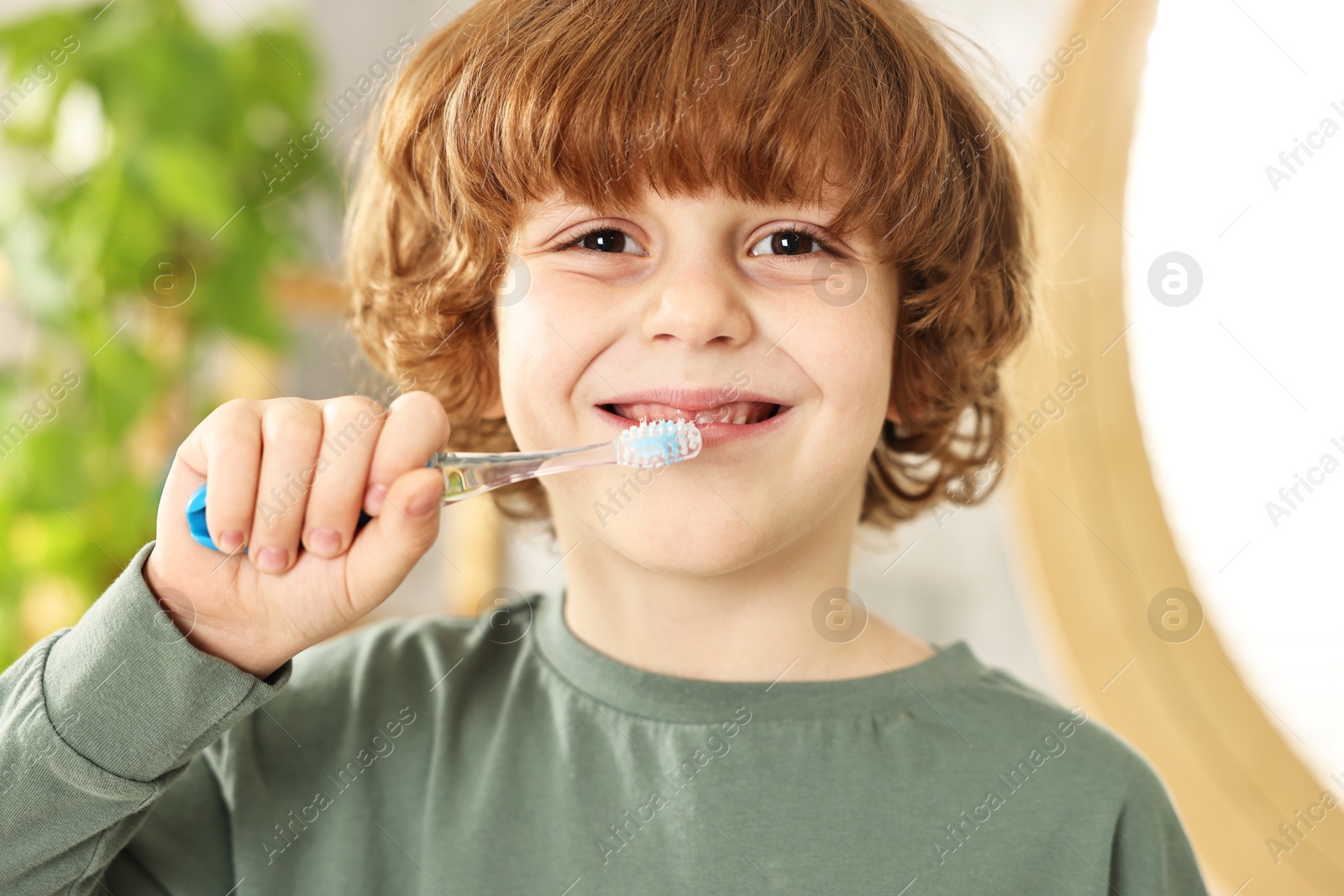 Photo of Cute boy brushing his teeth indoors, closeup