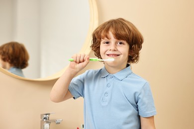 Photo of Cute boy brushing his teeth at home