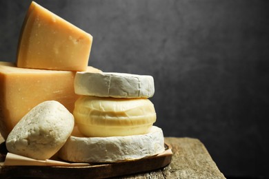 Photo of Different types of cheese on wooden table against grey background, closeup. Space for text