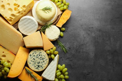 Photo of Different types of cheese, rosemary and grapes on dark textured table, flat lay. Space for text