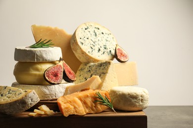 Photo of Different types of cheese, rosemary and figs on grey table, closeup. Space for text