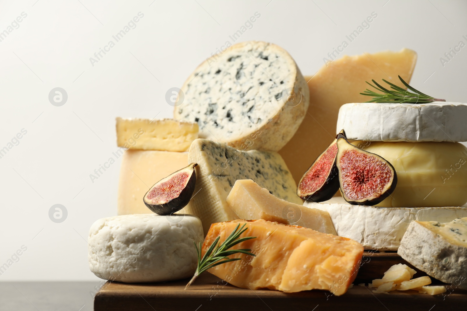 Photo of Different types of cheese, rosemary and figs on table, closeup