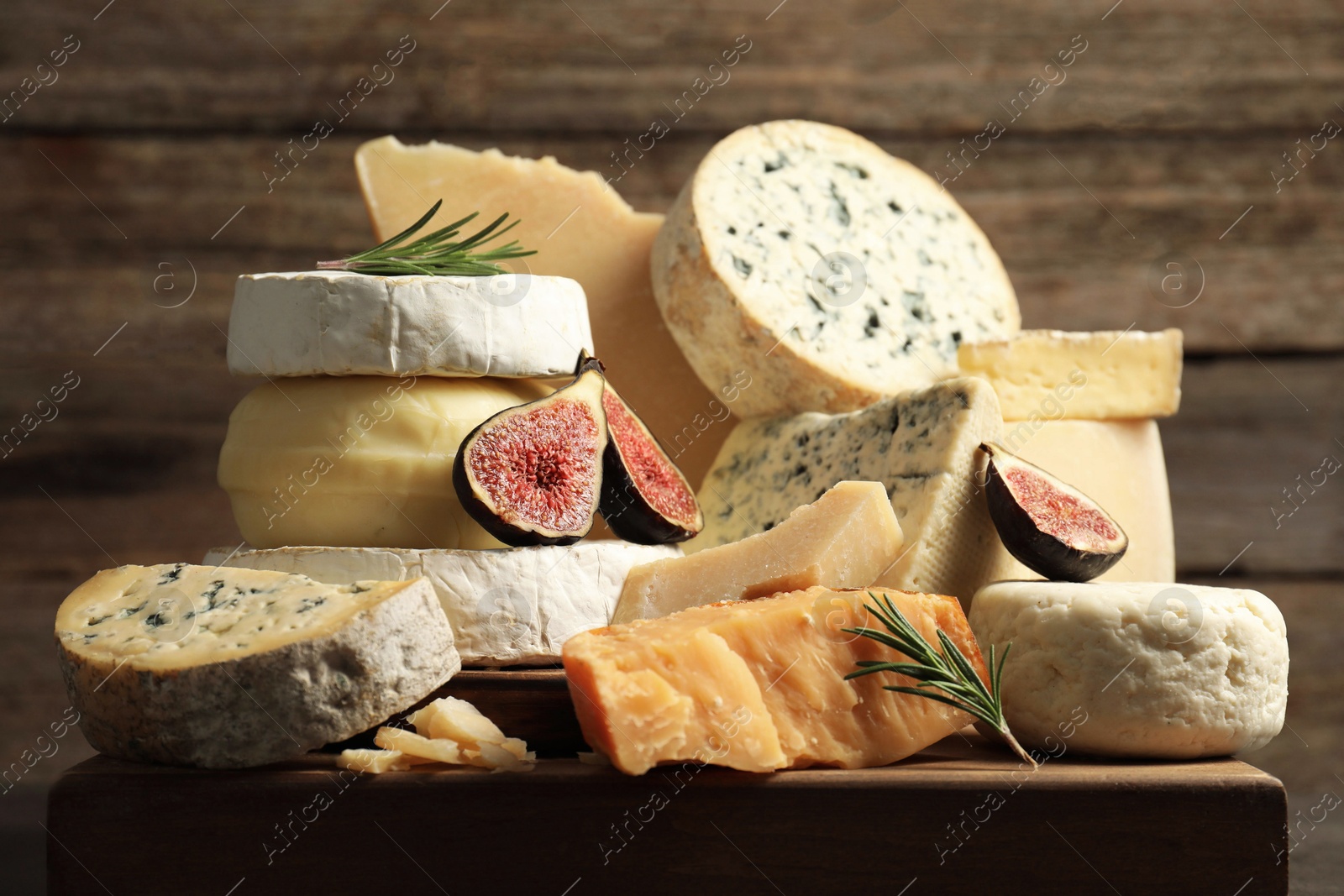 Photo of Different types of cheese, figs and rosemary on table, closeup