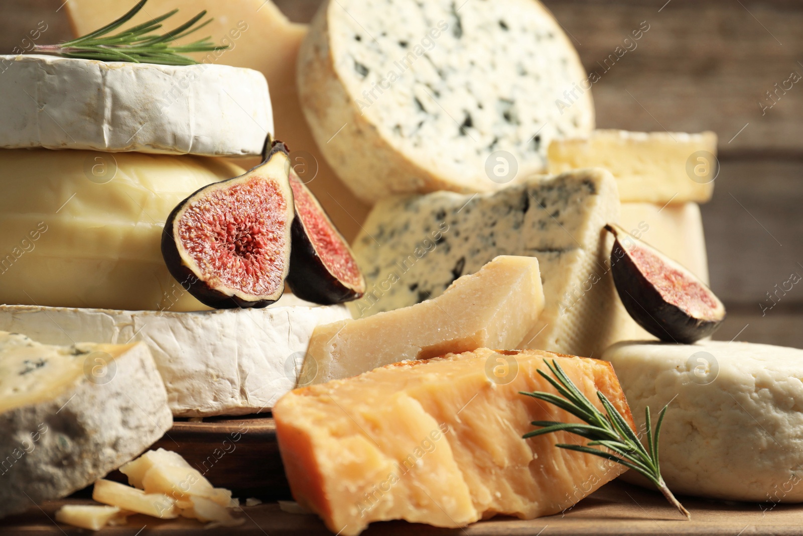 Photo of Different types of cheese, figs and rosemary on table, closeup