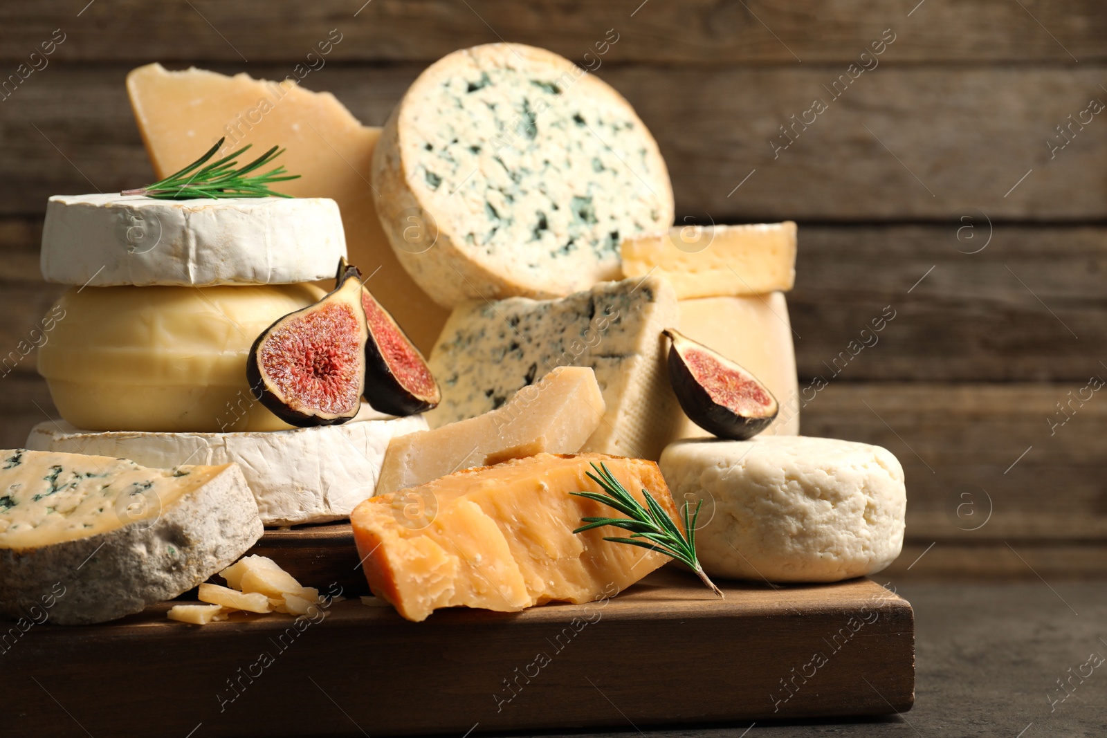 Photo of Different types of cheese, figs and rosemary on grey table, closeup