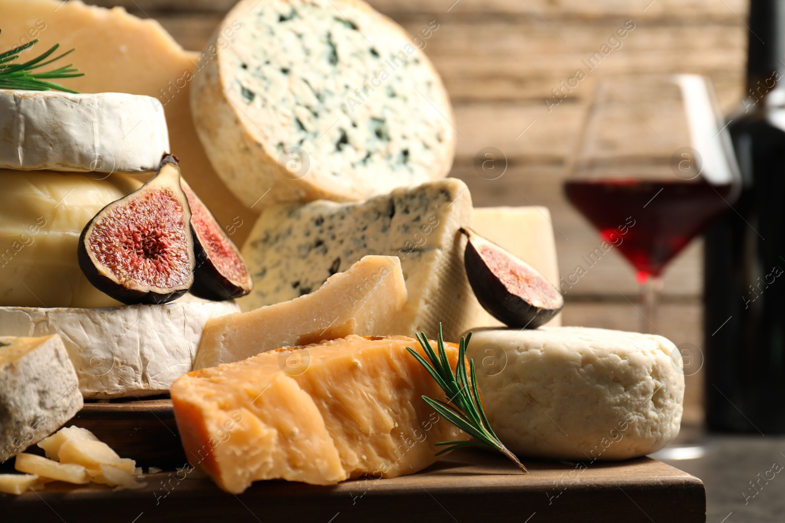 Photo of Different types of cheese, figs and rosemary on table, closeup