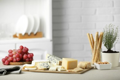 Photo of Different types of cut cheese and other snacks on light textured table indoors