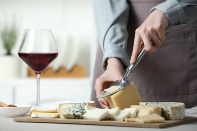 Photo of Woman slicing delicious cheese at light textured table indoors, closeup