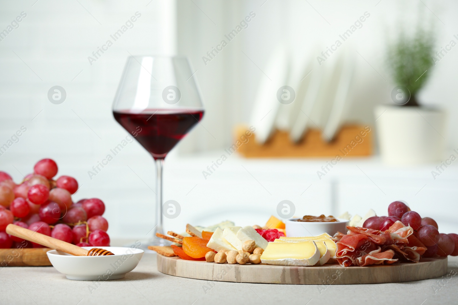 Photo of Different types of cut cheese and other snacks on light textured table, closeup