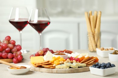 Photo of Different types of cut cheese and other snacks on light textured table, closeup