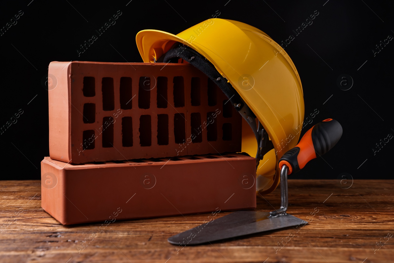 Photo of Bricks, hardhat and bucket trowel on wooden table