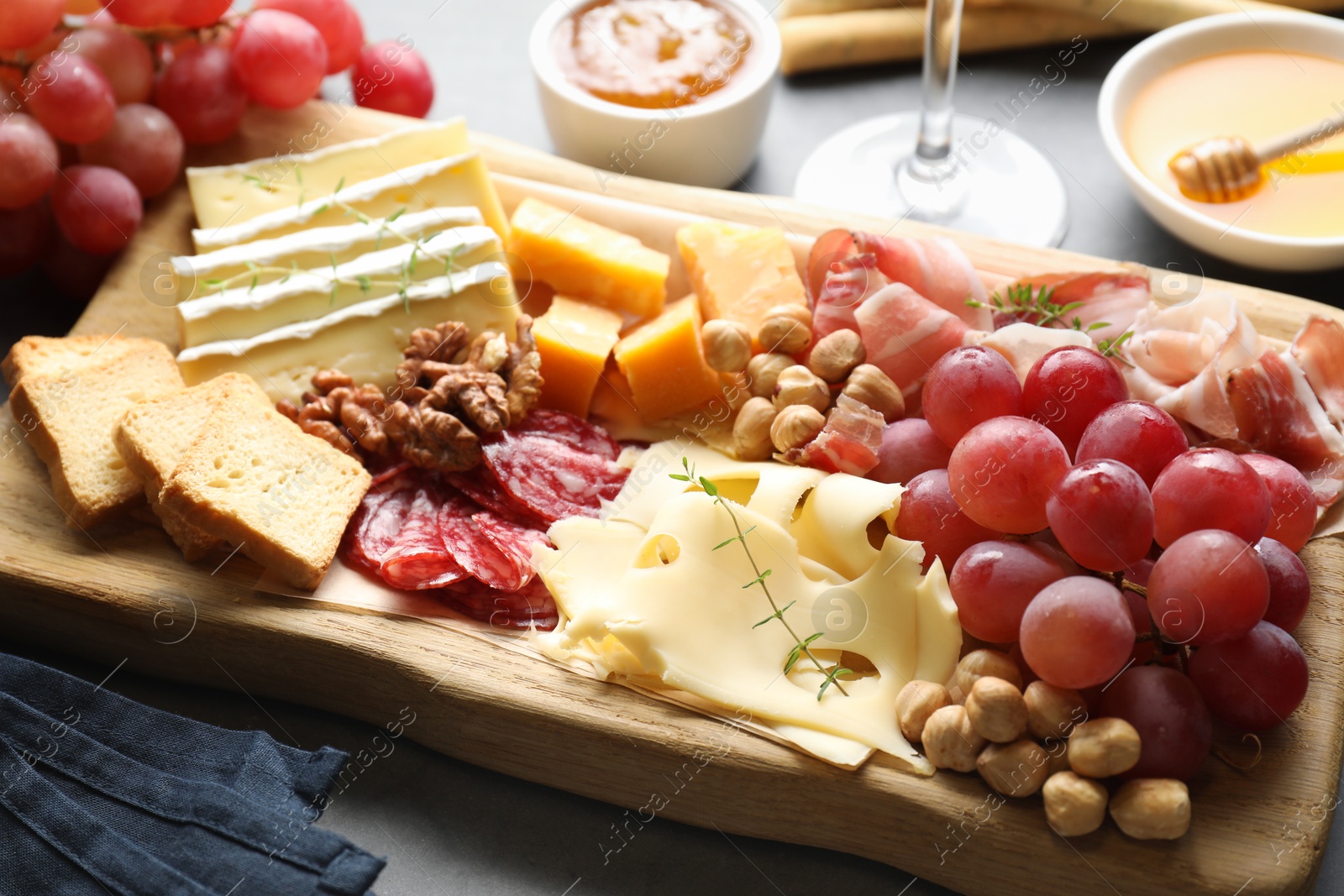 Photo of Different types of cut cheese and other snacks on gray table, closeup