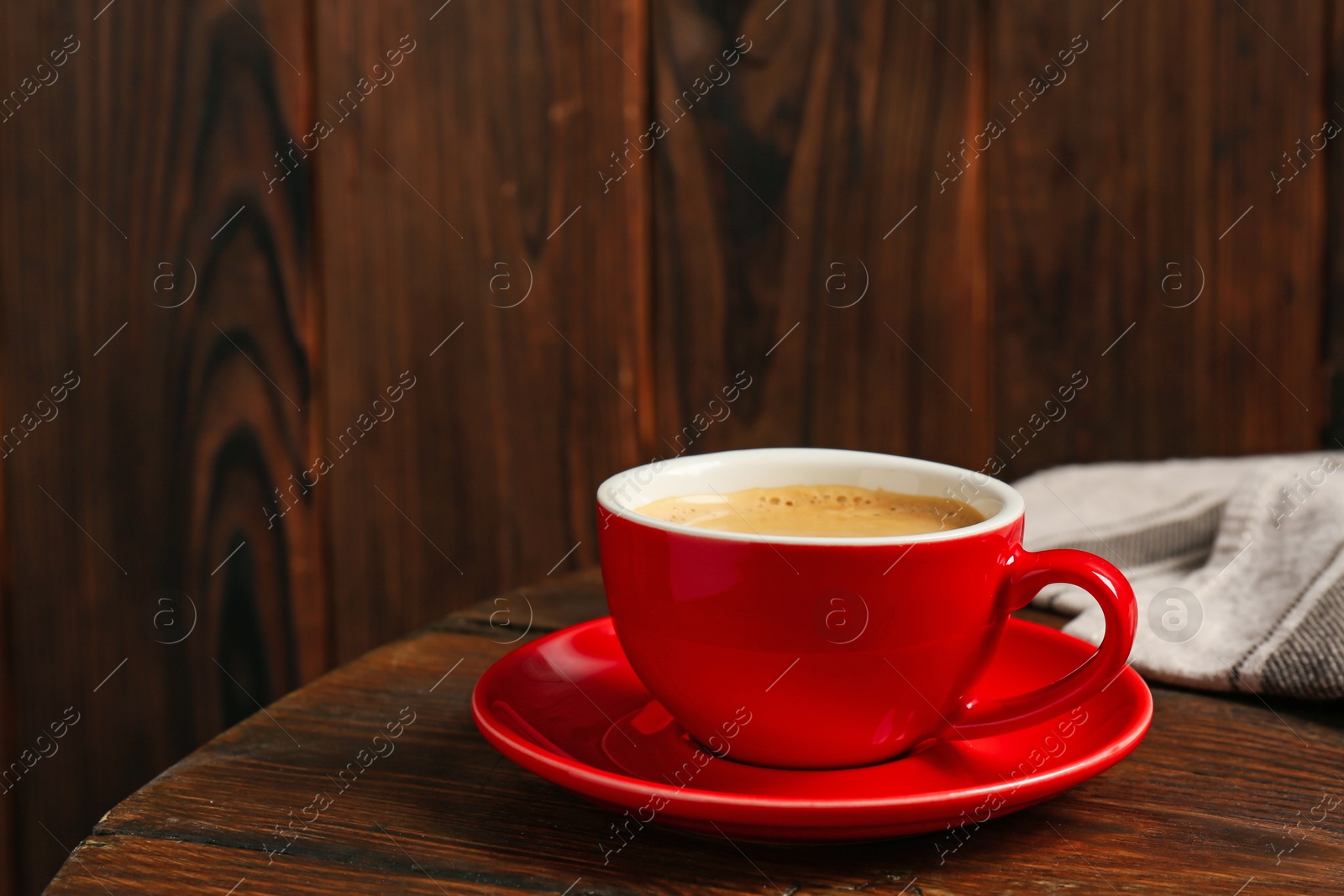 Red cup with coffee on wooden table, space for text Photo of Red cup with coffee on wooden table, space for text