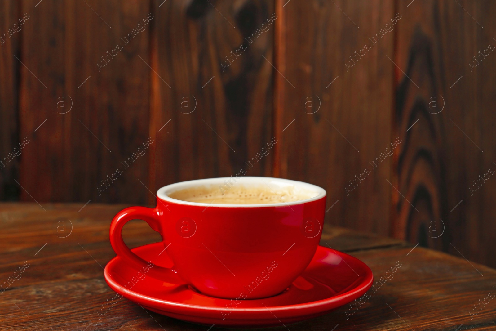 Red cup with coffee on wooden table Photo of Red cup with coffee on wooden table