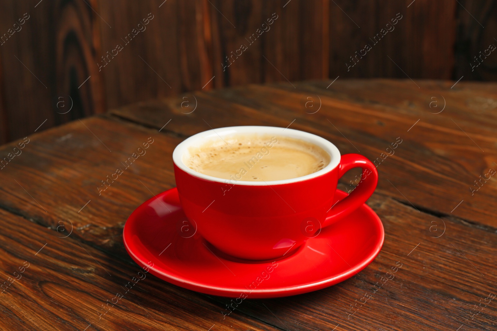 Red cup with coffee on wooden table Photo of Red cup with coffee on wooden table