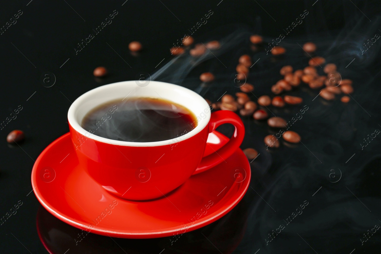 Red cup with coffee and roasted beans on black background, closeup. Space for text Photo of Red cup with coffee and roasted beans on black background, closeup. Space for text