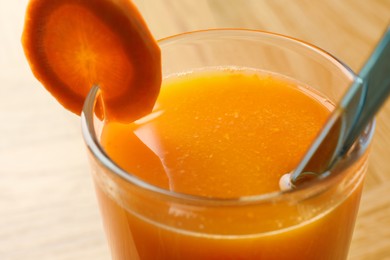 Fresh carrot juice in glass on light table, closeup