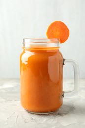 Fresh carrot juice in mason jar on gray textured table