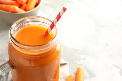 Fresh carrot juice in mason jar on gray table, closeup. Space for text