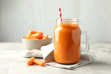 Photo of Fresh carrot juice in mason jar and vegetables on gray textured table