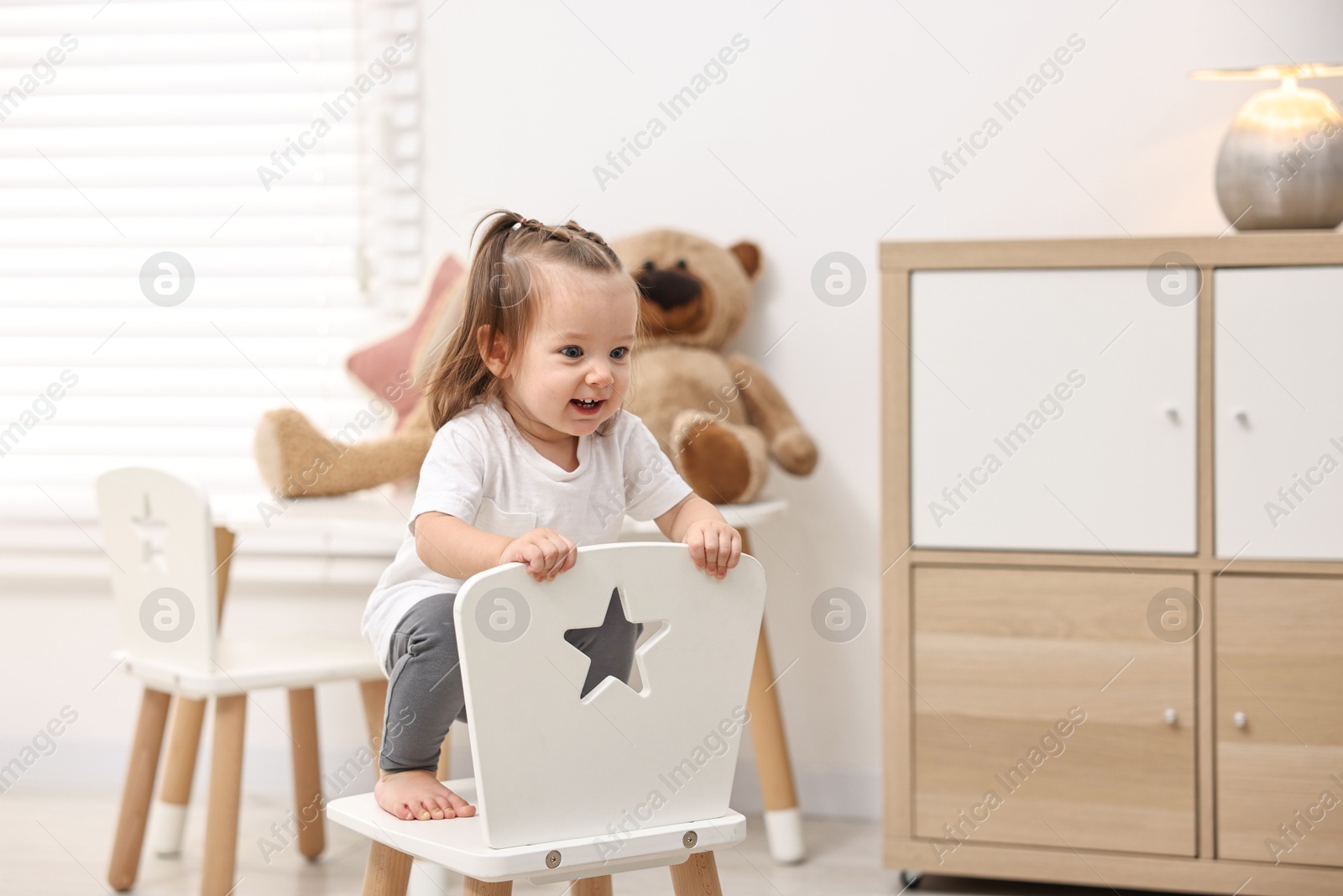 Photo of First steps. Cute little baby on small chair at home