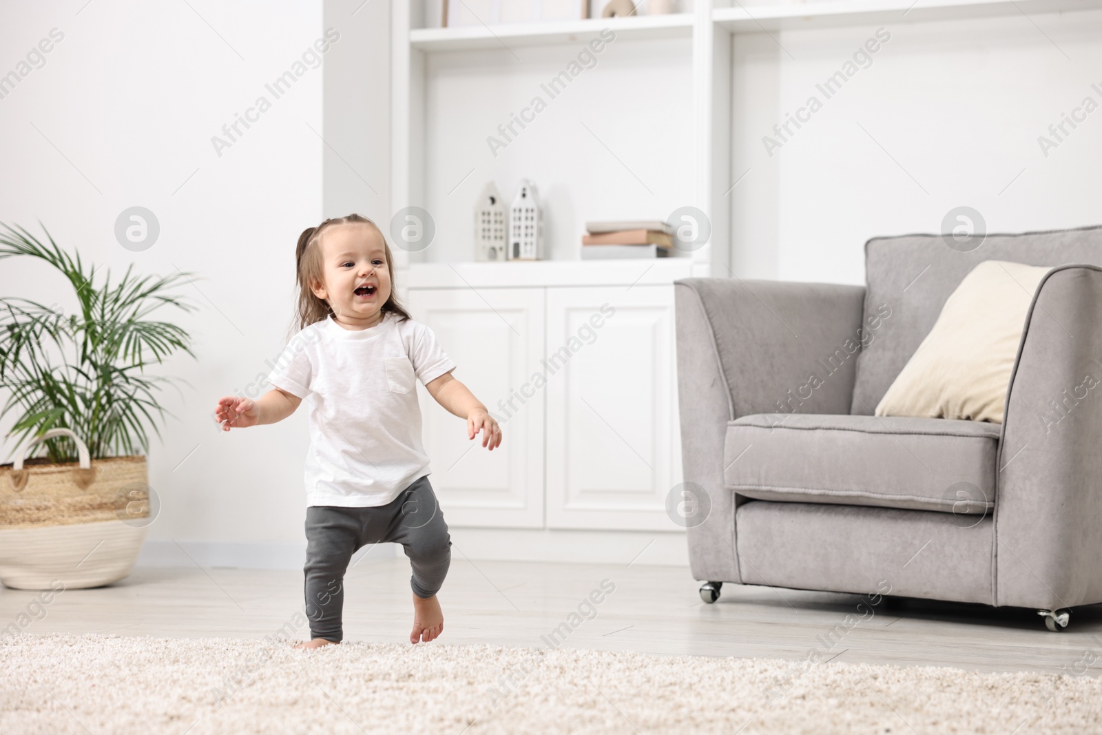 Photo of First steps. Cute little baby learning to walk at home