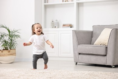 Photo of First steps. Cute little baby learning to walk at home