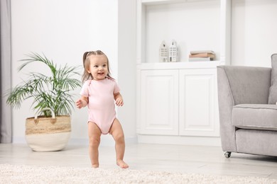 Photo of First steps. Cute little baby learning to walk at home