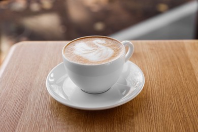 Photo of Cup of aromatic coffee on wooden table in cafe, closeup