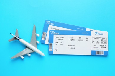 Photo of Travel agency. Flight tickets and plane model on light blue background, flat lay