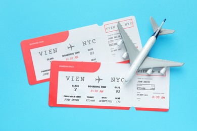 Photo of Travel agency. Flight tickets and plane model on light blue background, flat lay