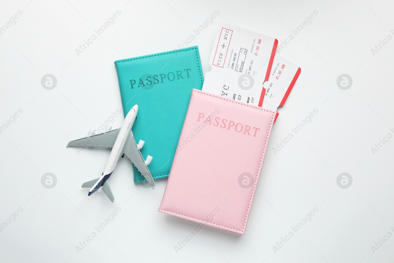 Photo of Travel agency. Flight tickets, passports and plane model on light background, flat lay