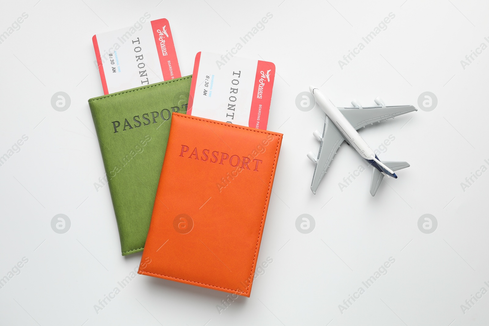 Photo of Travel agency. Flight tickets, passports and plane model on light background, flat lay